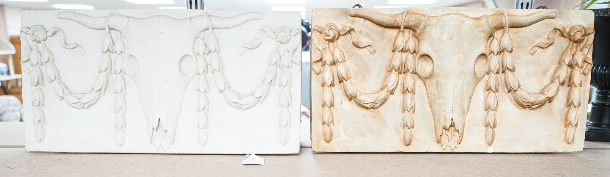 A composite simulated marble plaque, decorated with a skull and garlands, plus another (2) 25x50cm